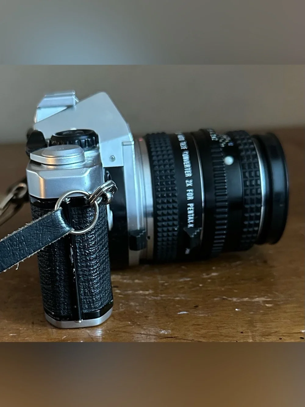 Pentax Silver and Black SLR Camera with Black Lens Cap and Colorful Strap